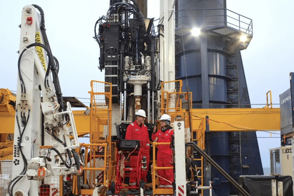 Совместные руководители экспедиции Брэндон Дуган из Колорадской горной школы и Ребекка Робинсон из Университета Род-Айленда беседуют на буровой площадке, наблюдая за контроллером насоса для откачки грунтовых вод. (Фото: Эрван ЛеБер, ECORD IODP³)