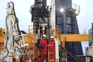 Совместные руководители экспедиции Брэндон Дуган из Колорадской горной школы и Ребекка Робинсон из Университета Род-Айленда беседуют на буровой площадке, наблюдая за контроллером насоса для откачки грунтовых вод. (Фото: Эрван ЛеБер, ECORD IODP³)